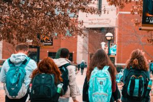 Students shown from behind wearing backpacks on a college campus.