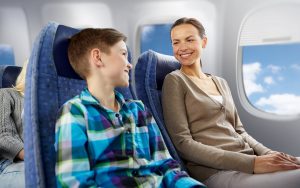 A smiling young boy and woman travelling on an airplane.