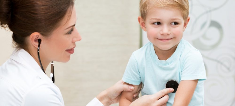 A doctor checks the heart beat of a little boy